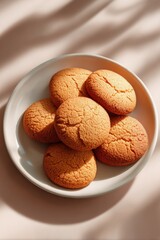 Golden shortbread cookies on white plate in natural light with shadows, top view of baked biscuits