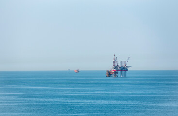 Seascape with offshore oil drilling platform that stands in the midst of a calm, blue sea.