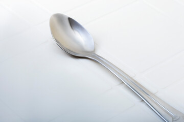 Stainless Steel Spoon on White Textured Surface