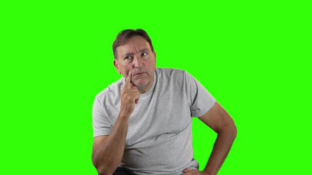 Man in gray shirt touches his face while deep in thought, looking upward as if trying to solve a problem or come up with an idea. Green screen allows full flexibility.  	