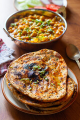 Amritsari kulcha is a crispy, flaky stuffed flatbread from Punjab, filled with spiced mashed potatoes or paneer, baked in a tandoor, and served hot with kabuli chana masala and salad
