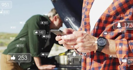 Two colleagues inspecting car engine roadside with smartphone, showing social icons for marketing - Powered by Adobe