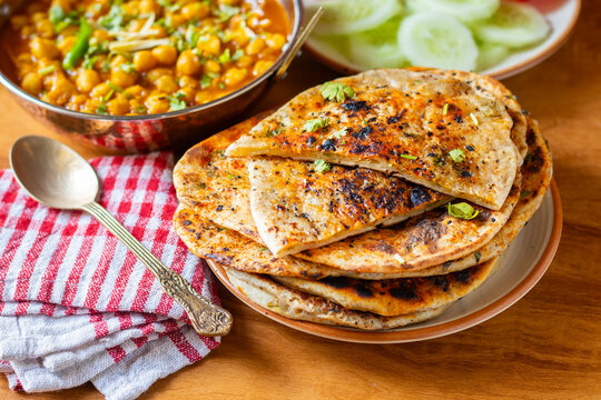 Amritsari kulcha is a crispy, flaky stuffed flatbread from Punjab, filled with spiced mashed potatoes or paneer, baked in a tandoor, and served hot with kabuli chana masala and salad
