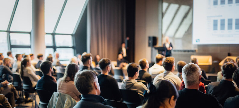 Speaker giving a talk in conference hall at business event. Rear view of unrecognizable people in audience at the conference hall. Business and entrepreneurship concept