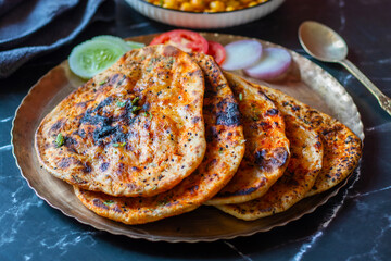 Amritsari kulcha is a crispy, flaky stuffed flatbread from Punjab, filled with spiced mashed potatoes or paneer, baked in a tandoor, and served hot with kabuli chana masala and salad
