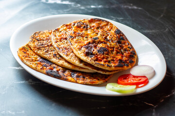 Amritsari kulcha is a crispy, flaky stuffed flatbread from Punjab, filled with spiced mashed potatoes or paneer, baked in a tandoor, and served hot with kabuli chana masala and salad
