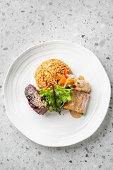 A gourmet meal featuring fried rice, glazed meat with sesame seeds, fresh greens, and a vegetable...