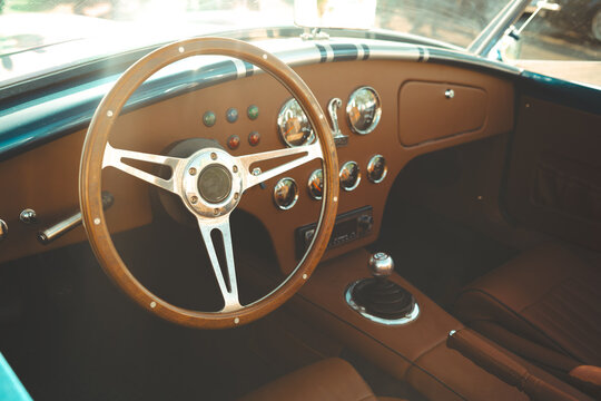 Fototapeta Vintage classic car interior featuring leather seats, chrome gauges, wooden steering wheel and polished dashboard