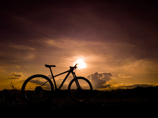 Silhouette Bike Ride: An adventurous bicycle is silhouetted against a dramatic, sunlit sky at dusk, painting a vivid picture of freedom, exploration, and the open road.
