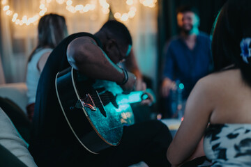 A close-knit group of friends enjoy playing acoustic guitar and sharing moments in a relaxed...