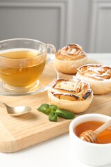 Freshly baked apple roses with mint, honey and tea on white table, closeup