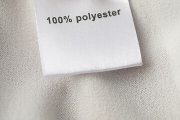 Clothing label with material content on beige garment, above view