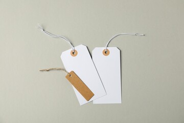 Naklejka premium Blank tags with strings on grey background, flat lay