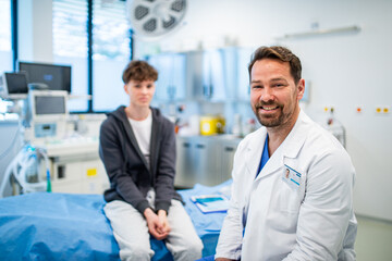 Portrait of doctor and teen boy during medical checkup in hospital room.