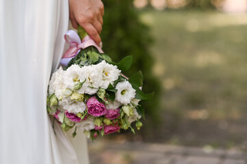 Brides In a white dress, hand holding fresh white bouquet, delicate petals. Wedding morning...