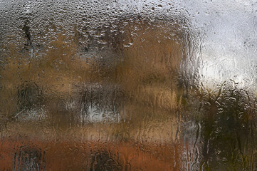 wet glass background. Humid air fogs up glass, turning it into canvas for nature art. Water drops merge into abstract shapes, blurring the line between inside and outside.