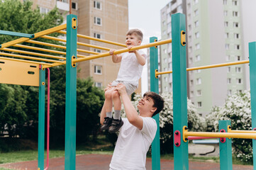 Older and younger brothers doing sports together on outdoor fitness ground. Active lifestyle, family values, childhood health and physical development.