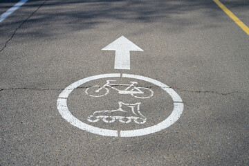 Fototapeta premium white sign for cyclists and rollerbladers on asphalt path in park