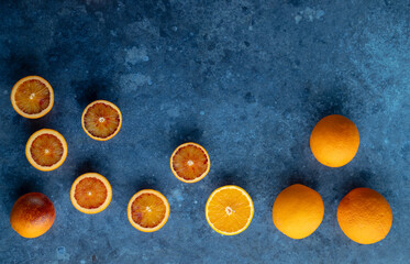 Fresh oranges and slices on textured surface