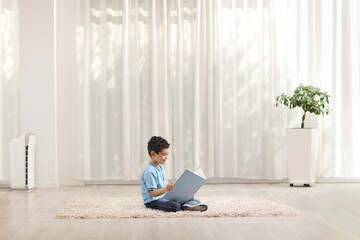 Boy sitting on a carpet in a room