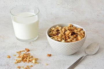 A portion of granola with milk and a spoon on the side