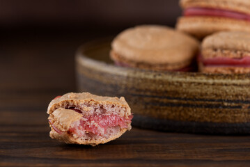 Homemade French caramel macaroons with raspberry cream on shea butter on a brown wooden table. Vegan, healthy dessert. Sugar, lactose and gluten free.