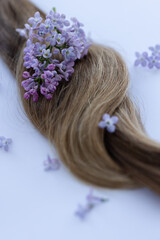Naklejka premium Hair with lilac flowers. Closeup, selective focus.