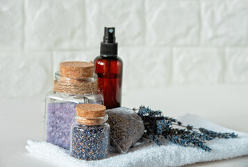 Lavender Spa Set with Dried Flowers and Bath Salts. Relaxing Spa Arrangement. Lavender flowers, bath salts, dried buds in glass jars, spray bottle, and sachet on white towel