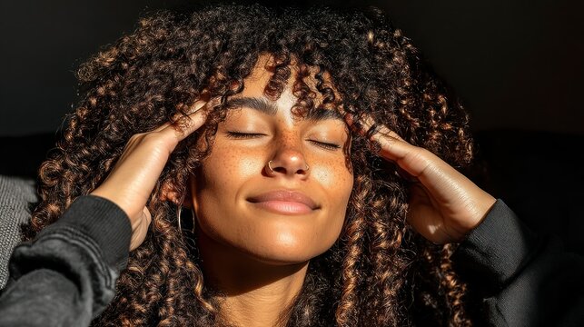 Curly haired woman with sunlight, freckles, eyes closed