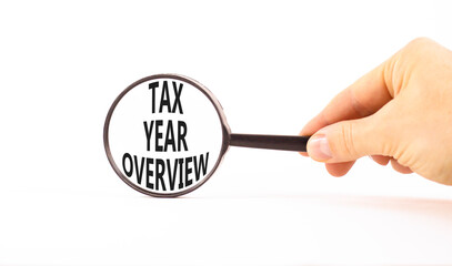 Tax year overview symbol. Concept words Tax year overview on beautiful black magnifying glass. Beautiful white background. Businessman hand. Business tax year overview concept. Copy space.