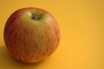 manzana entre verde y roja en un fondo amarillo
