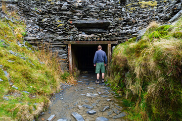 A man is walking next to a slate mine tunnel entrance