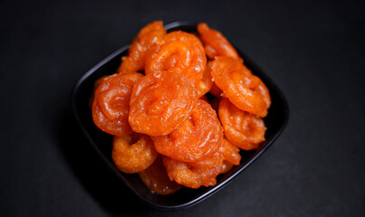 Traditional Indian Sweet Jalebi on a plate dipped in sugar syrup black background