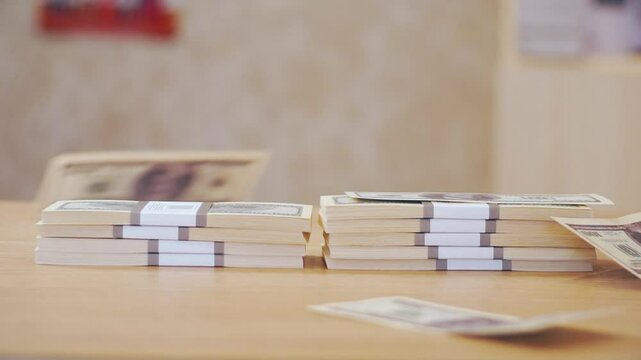 close-up of two stacks of dollars with $100 bills falling on top