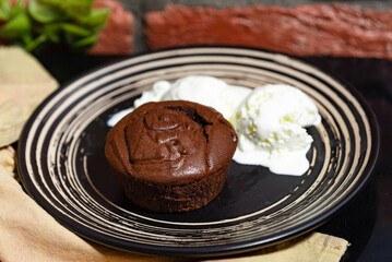 Chocolate Lava Cake with Vanilla Ice Cream. Rich chocolate lava cake served warm with melting scoops of vanilla ice cream on a black dessert plate.