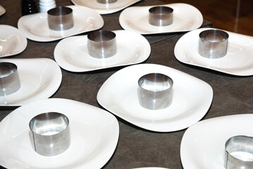 Empty plates with stainless steel food rings. Preparing to make salad portions.