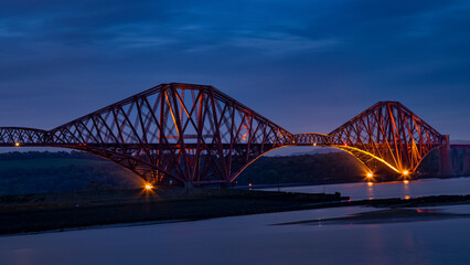 Obraz premium The Forth Bridge is illuminated at night in Scotland