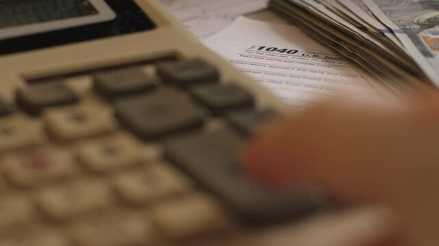 Tax Form 1040, Calculator and Hundred Dollar Bills, Concept of Tax Payment by US Citizen