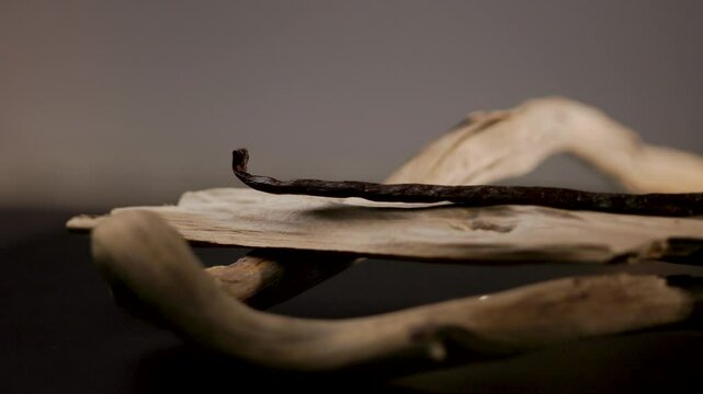 Gousse de vanille pos&eacute;e sur du bois, plan fixe avec variations de lumi&egrave;re