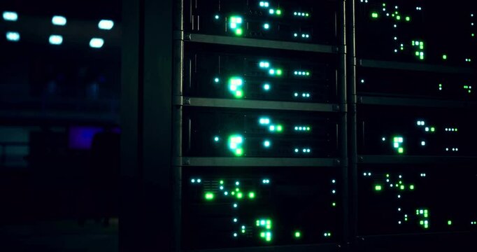 High tech server room illuminated by green and blue lights. Equipment is lined up in rows, showcasing technological activity and data processing after hours.