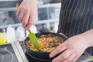 The chef cooks pasta in a frying pan. 