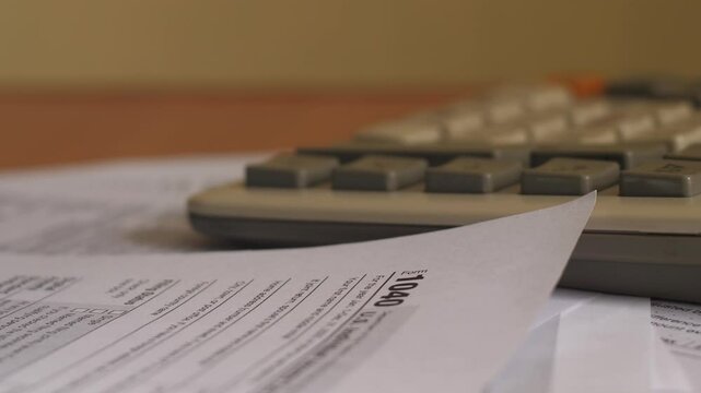 financial reporting and tax payment, featuring a tax form 1040, a calculator, and U.S. dollar cash bills.  calculations, monetary transactions, and responsible financial management