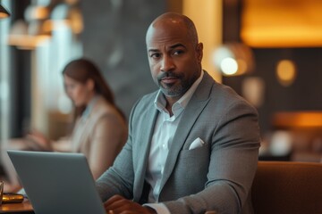 Obraz premium Confident businessman works on laptop in modern cafe, showcasing professionalism and success.