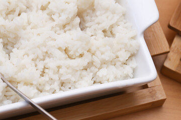Steamed white rice served. Hot rice in ceramic dish. Healthy cooked side dish. Traditional Asian meal. Plain boiled rice ready to eat. Simple food on wooden table. Warm vegetarian dinner base.