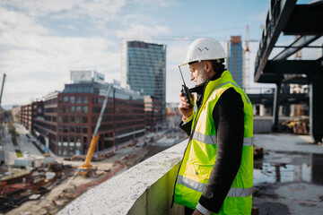 Site manager giving instructions over radio during building inspection.