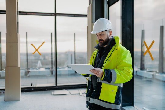 Construction site manager using digital tablet to inspect building progress.