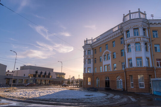 Historic Soviet-era building on Karl Marx Street, Petrozavodsk, Karelia, Russia, with wet road reflections on a sunny spring evening.
