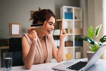 Obraz premium Woman celebrating successful online purchase at home desk