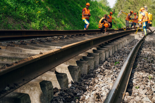 A worker in the process of arailroad track weld repair with a freight train passing
