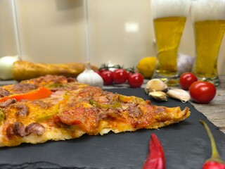 slice of pizza is on a plate next to a glass of beer